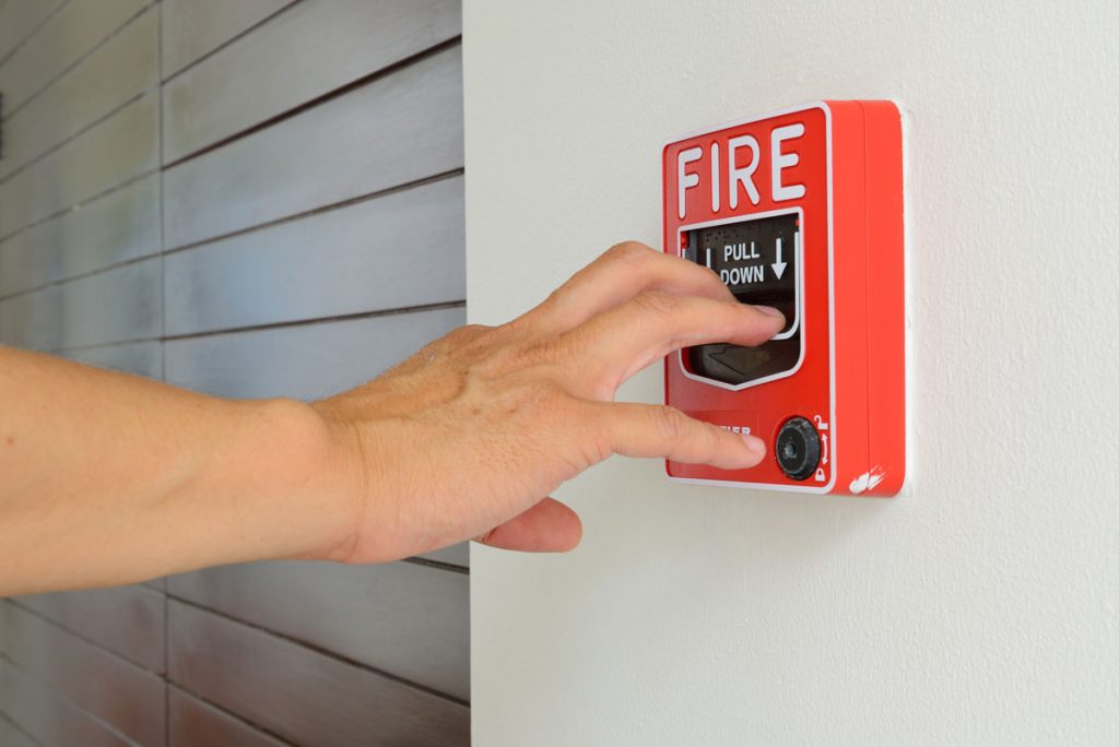 a hand pulling a fire alarm system in Jacksonville, Jacksonville Beach, Davie, Fort Lauderdale, Coral Springs, Coconut Creek